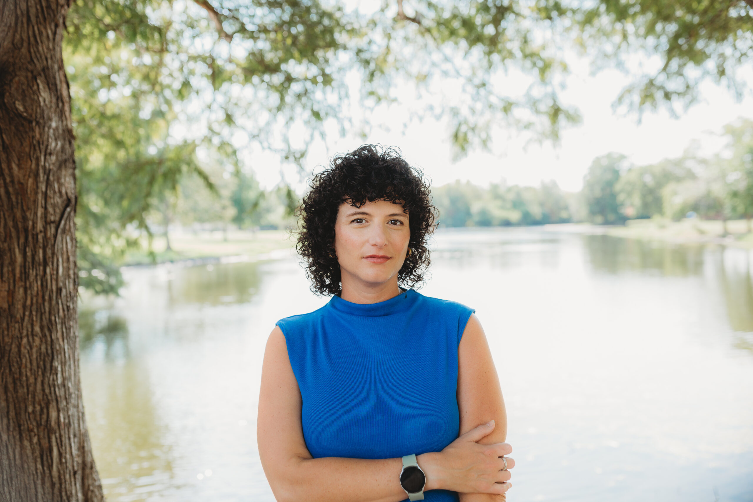 Mor Sheinbein of Shein Writing standing in front of a tree and lake in blue dress